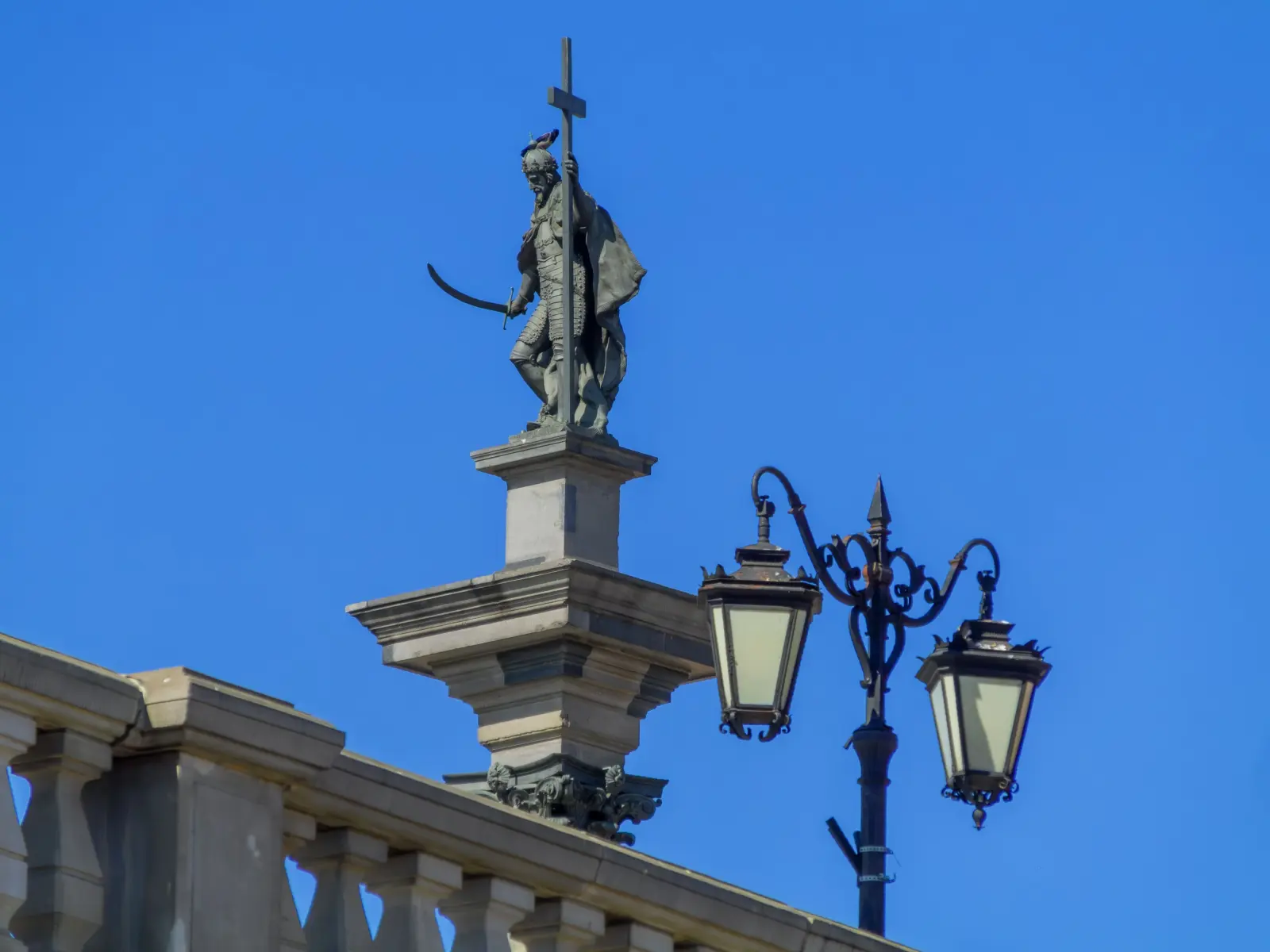 Warszawski detal architektury: figura i latarnia na tle nieba